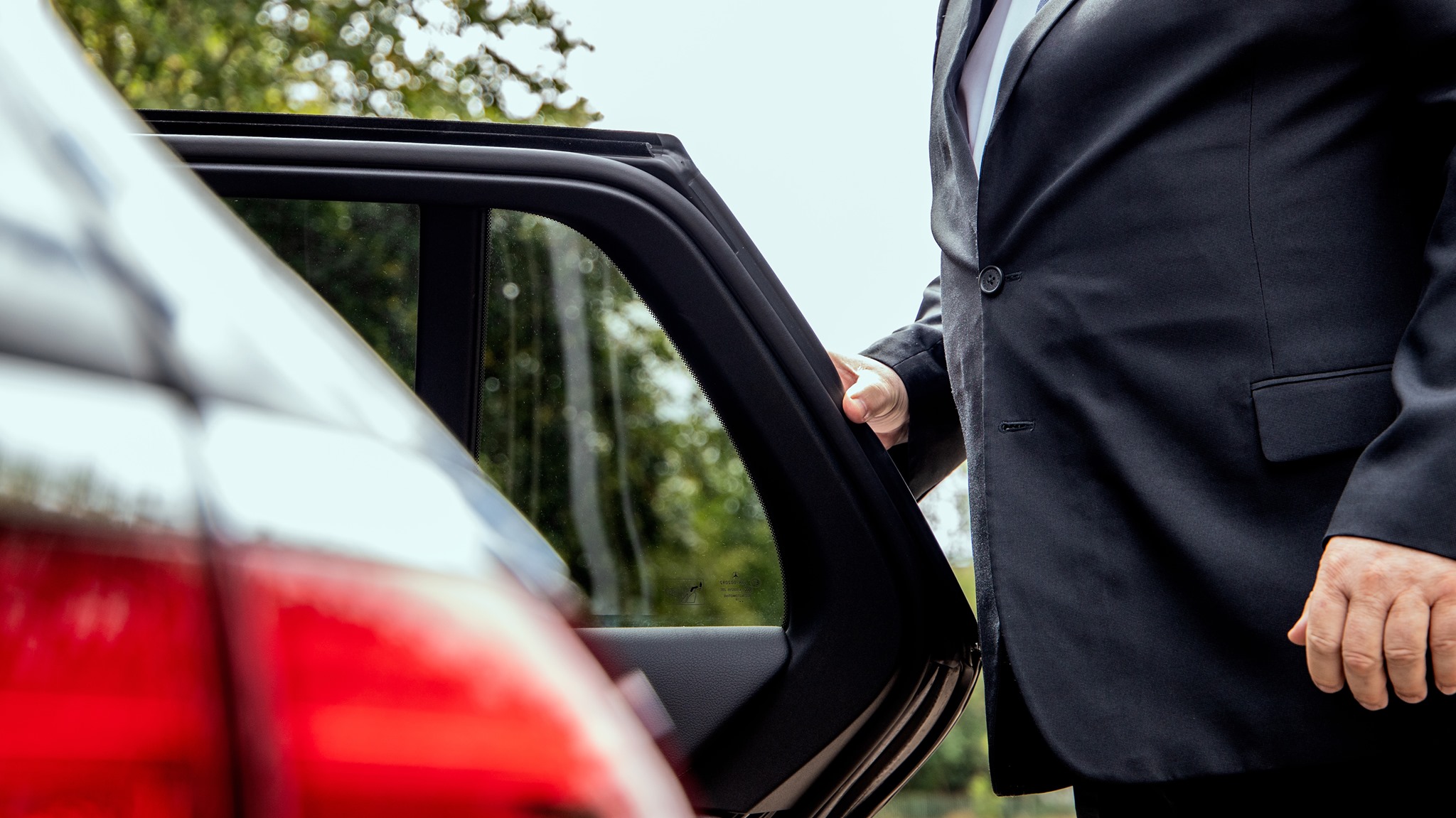 chauffeur opening door for private traveling passenger